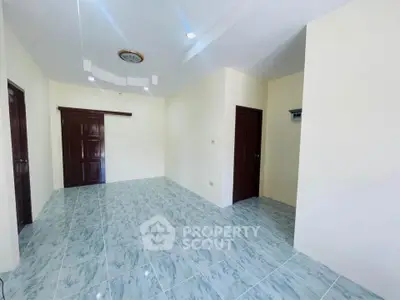 Spacious empty room with tiled flooring and wooden doors, ideal for customization.