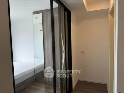 Modern bedroom with mirrored wardrobe and wooden flooring