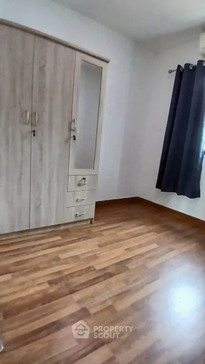 Spacious bedroom with wooden flooring and large wardrobe, perfect for modern living.