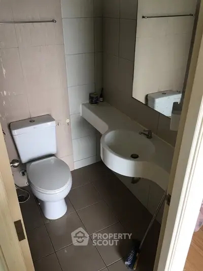 Compact bathroom with modern fixtures and tiled walls, featuring a sleek sink and toilet.