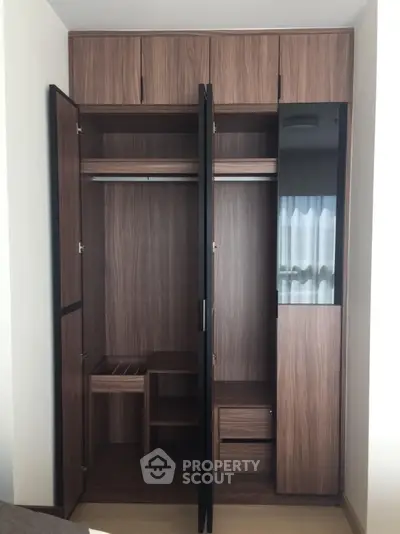 Modern wooden wardrobe with open doors showcasing ample storage space in a stylish bedroom.