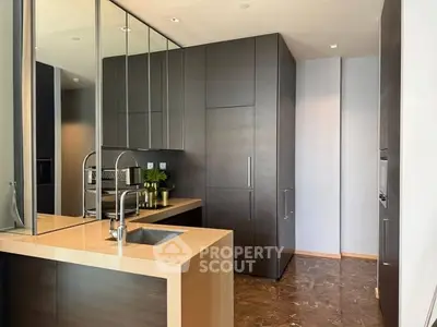 Modern kitchen with sleek dark cabinetry and marble flooring, featuring a stylish open layout and built-in appliances.