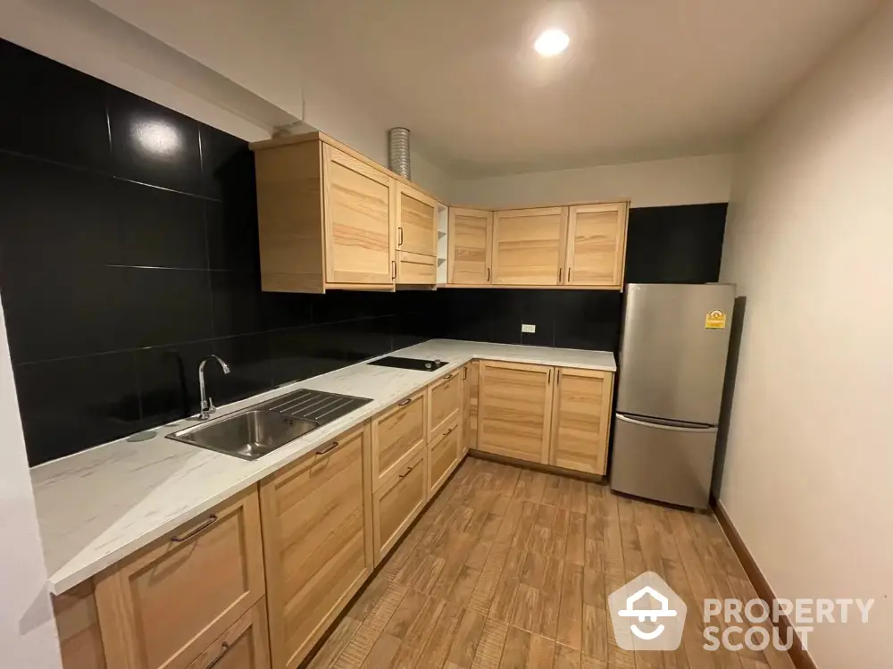 Modern kitchen with wooden cabinets and sleek black backsplash