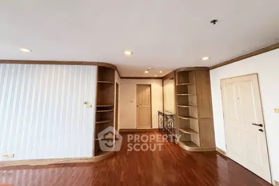 Spacious living room with elegant wooden flooring and built-in shelves.
