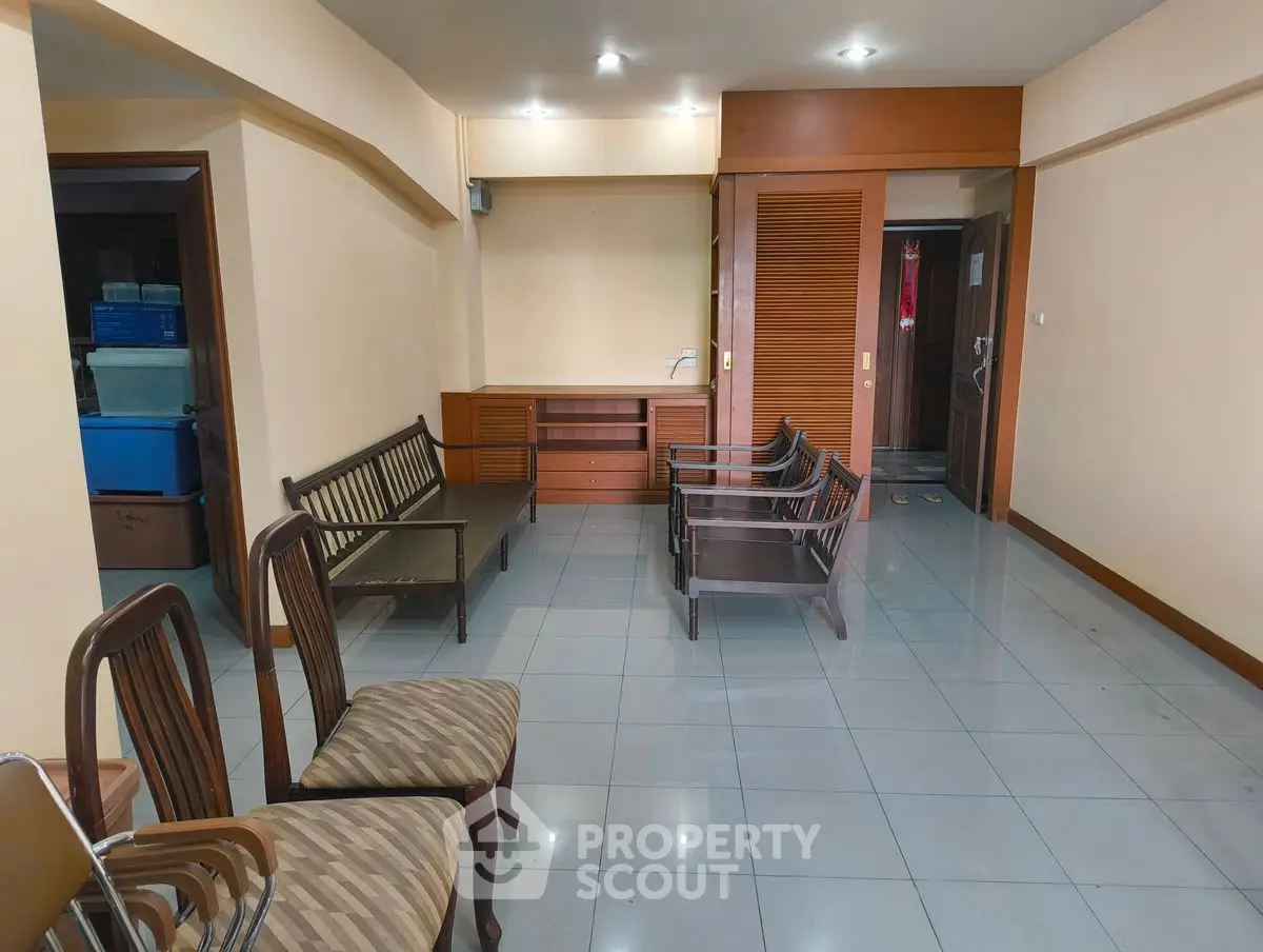 Spacious living room with wooden furniture and tiled flooring in a modern apartment.