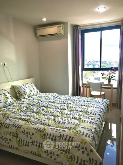 Cozy bedroom with large window and city view, featuring modern decor and natural light.