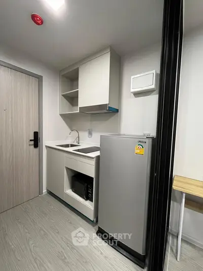 Modern compact kitchen with sleek cabinetry and stainless steel appliances in a stylish apartment.
