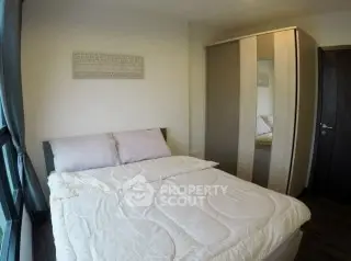 Cozy bedroom with modern wardrobe and large window offering natural light.