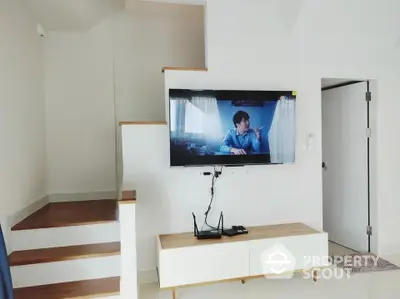 Modern living room with wall-mounted TV and sleek wooden staircase