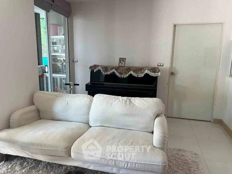 Cozy living room with white sofa and piano, perfect for relaxation and music lovers.