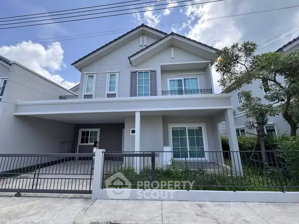 Modern two-story house with a spacious driveway and lush greenery.