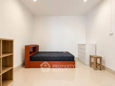 Minimalist bedroom with wooden bed frame and modern furniture in bright, spacious interior.
