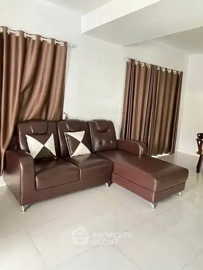 Spacious living room with elegant brown leather sofa and modern curtains