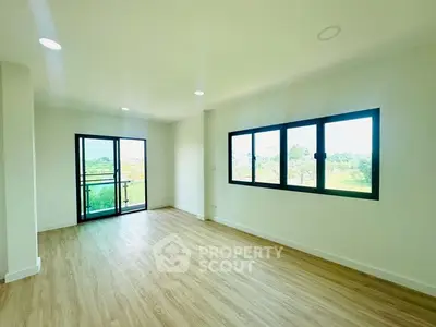 Spacious living room with large windows and scenic views, featuring elegant wooden flooring.