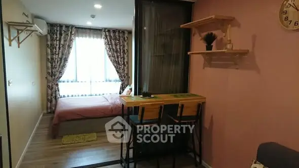 Cozy bedroom with stylish decor and natural light, featuring a small dining area and modern furnishings.