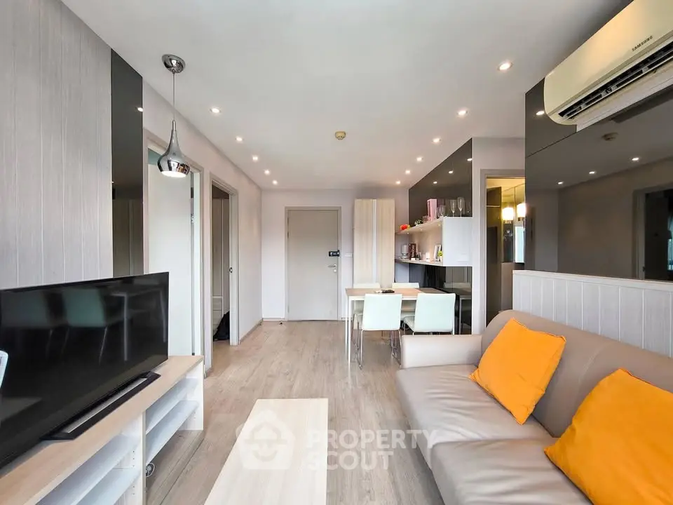 Modern living room with sleek furniture and air conditioning, featuring a cozy dining area and stylish decor.