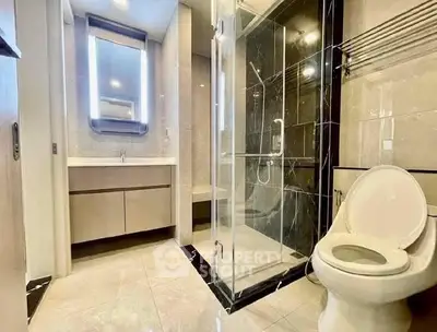 Modern bathroom with glass shower and sleek fixtures in luxury apartment.