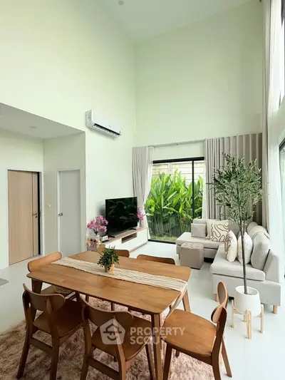Spacious modern living room with high ceilings and large windows overlooking lush greenery.