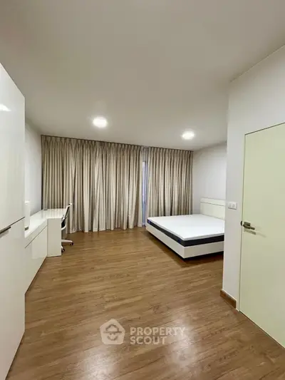 Spacious modern bedroom with wooden flooring and minimalist design