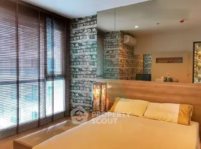 Modern bedroom with stylish brick accent wall and large window blinds.