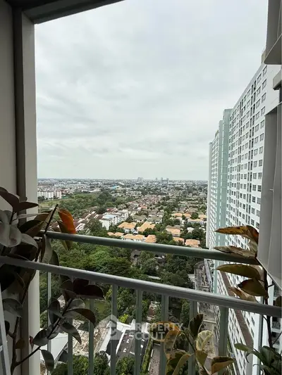Stunning balcony view from high-rise apartment overlooking cityscape and greenery.