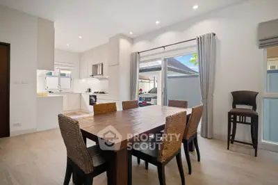 Spacious dining area with wooden table and modern kitchen in open layout design.
