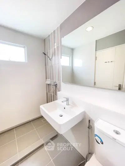 Modern bathroom with sleek fixtures and natural light, featuring a stylish sink and shower area.