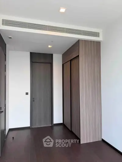 Modern minimalist bedroom with sleek wooden flooring and built-in wardrobe