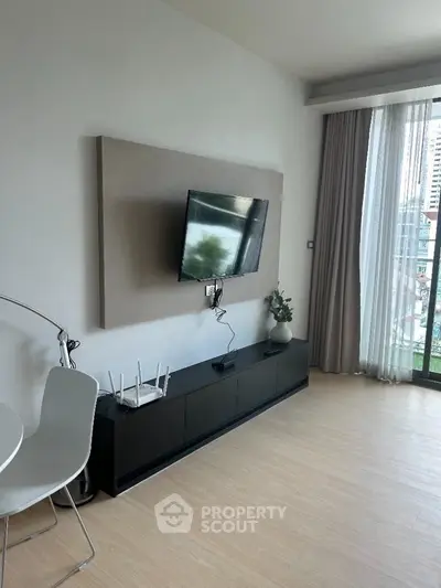 Modern living room with wall-mounted TV and stylish decor in a bright apartment.