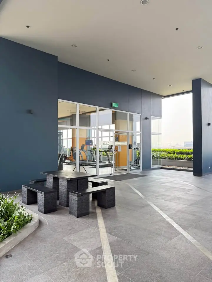 Modern gym entrance with outdoor seating and greenery