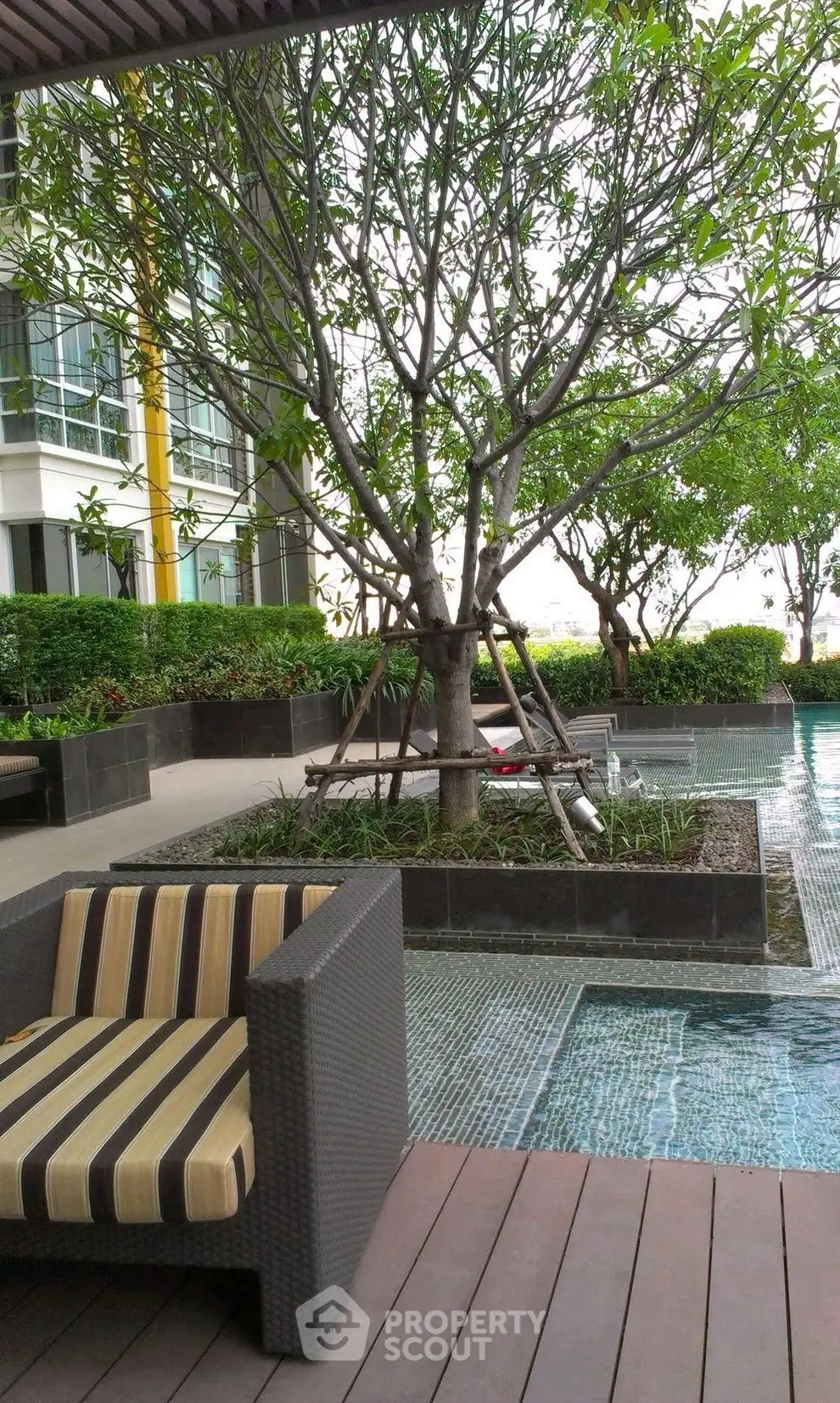 Luxurious poolside area with stylish seating and lush greenery in modern residential complex.