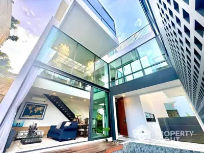 Stunning modern home with glass facade and spacious open-plan interior, featuring elegant lighting and stylish decor.