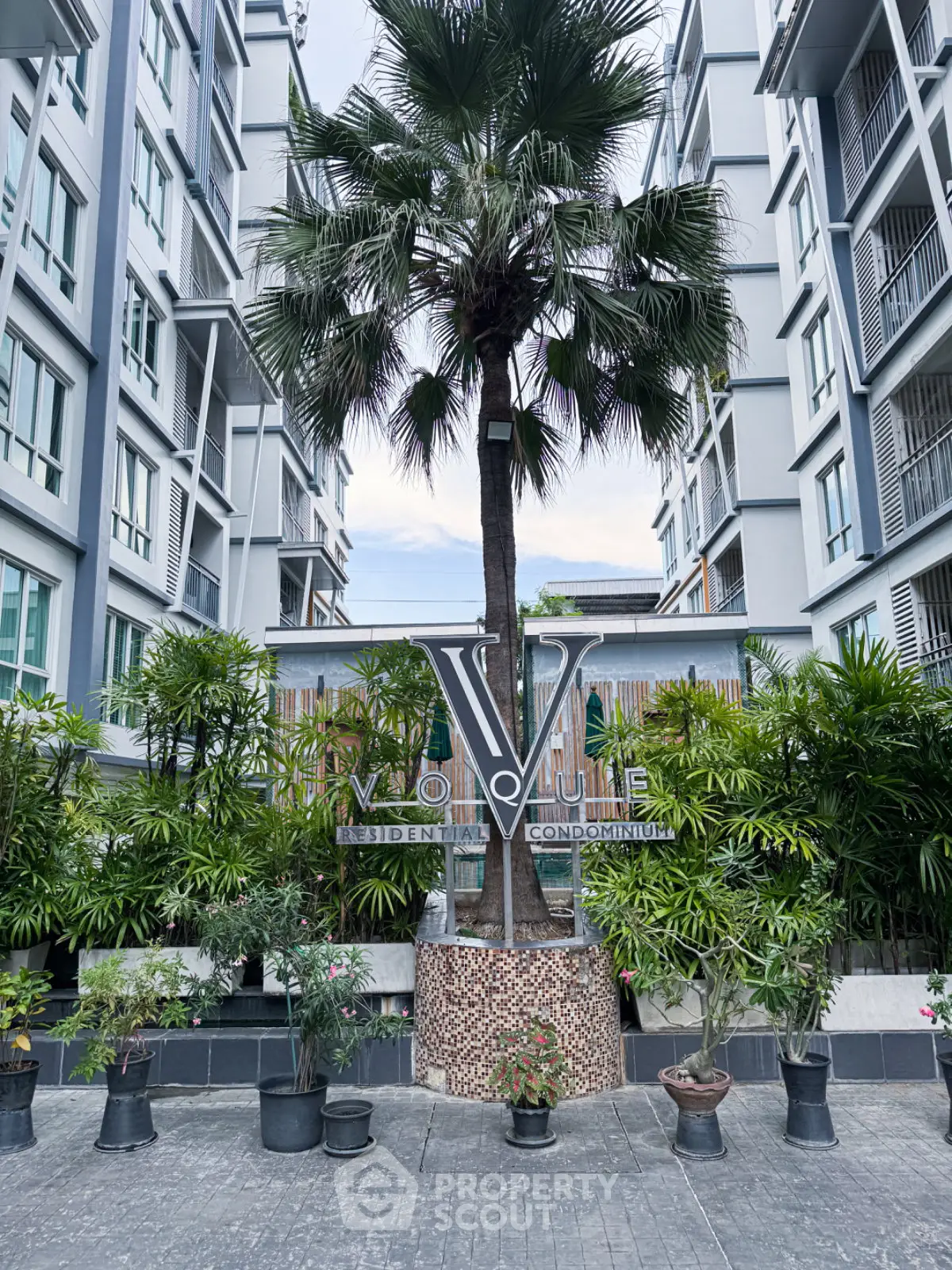 Modern condominium entrance with lush greenery and stylish architecture