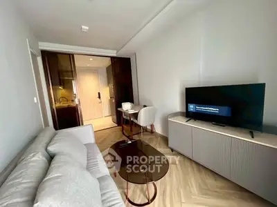 Modern living room with sleek furniture and open layout, featuring a cozy sofa and flat-screen TV.