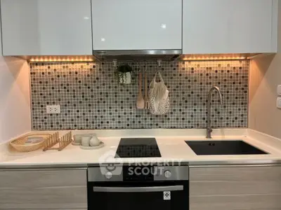 Modern kitchen with sleek design, induction cooktop, and stylish backsplash.