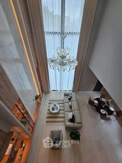 Luxurious high-ceiling living room with elegant chandelier and modern decor