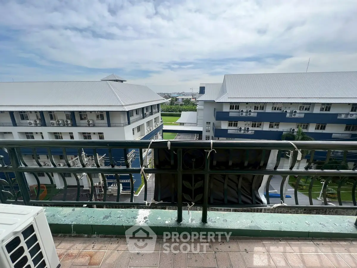 Spacious balcony with scenic view of modern buildings and lush greenery.