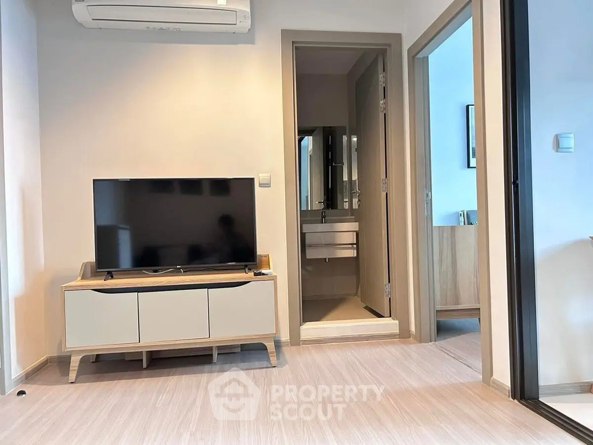 Modern living room with sleek TV stand and air conditioning, adjacent to a bathroom.