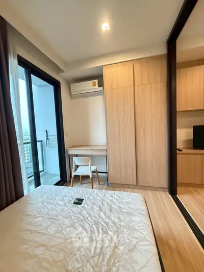 Modern bedroom with balcony access and built-in wardrobe in a high-rise apartment.