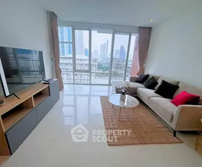 Spacious living room with modern decor and city view, featuring a large TV and comfortable seating.