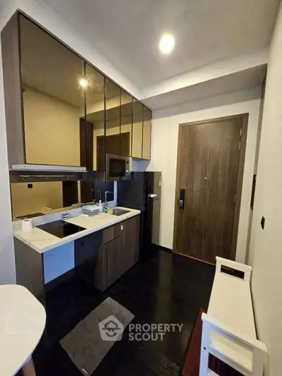 Modern compact kitchen with sleek cabinetry and integrated appliances in a stylish apartment.