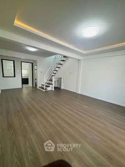 Spacious modern living room with wooden flooring and staircase in a stylish home.