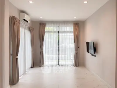 Spacious modern living room with large windows and wall-mounted TV