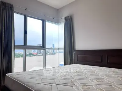 Spacious bedroom with large window offering stunning city and river views.