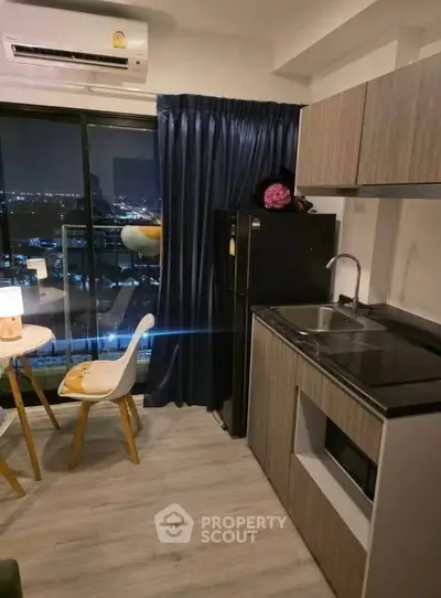 Modern kitchen with city view, sleek cabinetry, and cozy dining area in urban apartment.