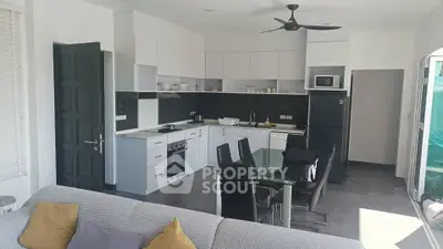 Modern open-plan kitchen with sleek design and dining area, featuring contemporary appliances and stylish decor.