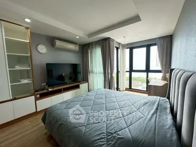 Spacious bedroom with modern decor and large windows offering natural light.