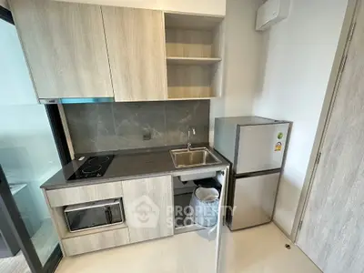 Modern compact kitchen with sleek cabinetry and stainless steel appliances in a stylish apartment.