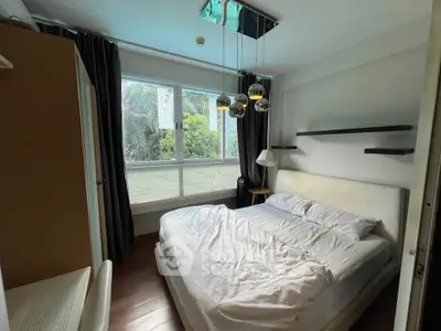 Cozy bedroom with large window and modern lighting in a stylish apartment.
