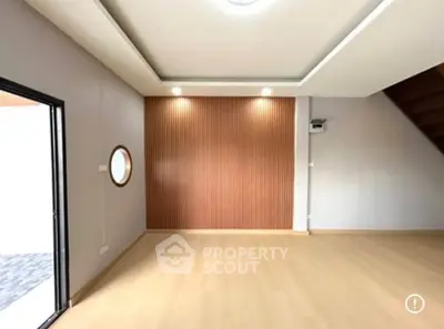 Spacious modern living room with wooden flooring and stylish wall paneling.